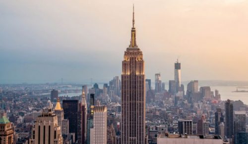 Aerial view of the empire state building at sunset with the new york city skyline in the background.