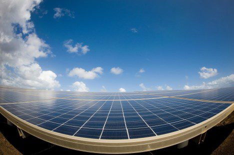 A wide-angle view of a large solar panel array under a partly cloudy sky.