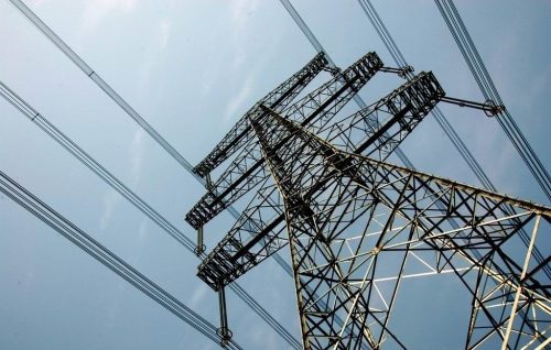 Low angle view of a large electricity pylon with multiple cables against a clear sky.