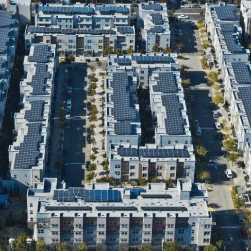 Aerial view of a modern residential area with buildings equipped with solar panels on rooftops.