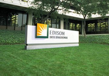 Signboard of edison international with a logo, positioned in front of a building surrounded by a green lawn.
