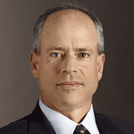 Portrait of a middle-aged caucasian man with a short haircut, wearing a suit and tie, against a neutral background.