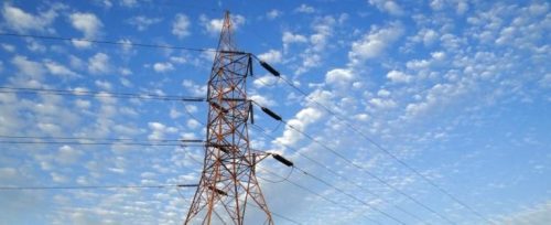 Electricity pylon against a blue sky scattered with white fluffy clouds.