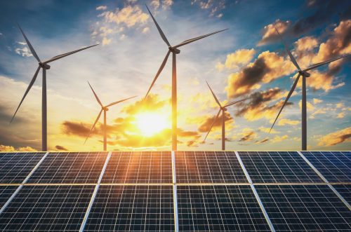 Solar panels and wind turbines against a sunset sky, symbolizing renewable energy sources.