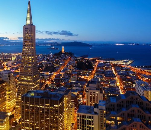 Aerial view of san francisco at dusk, featuring the transamerica pyramid and well-lit city streets leading to the bay.