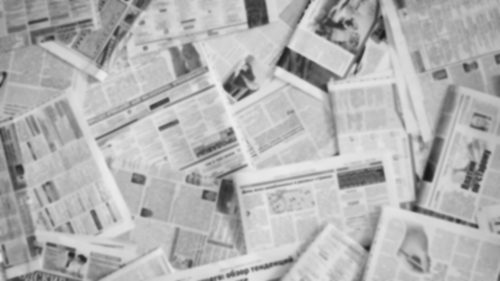 Blurred image of various scattered newspaper pages.
