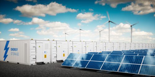 A renewable energy setup with rows of solar panels in the foreground and wind turbines in the back, next to large energy storage units under a blue sky.