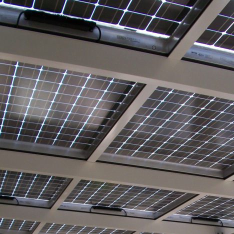 Solar panels installed on a building's roof visible through a glass ceiling.
