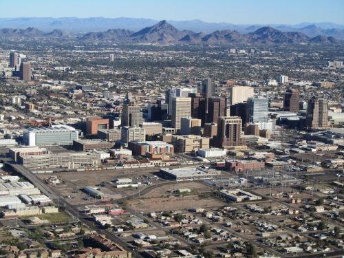 Aerial view of downtown phoenix, arizona, showing high-rise buildings, streets, and surrounding desert landscape.