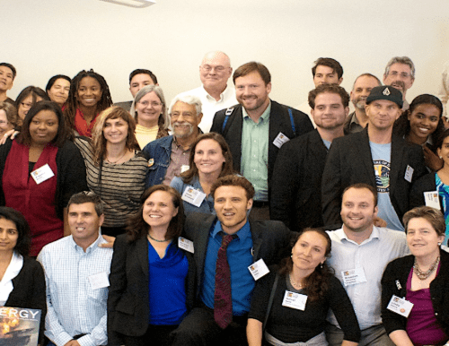 Group of diverse adults in a conference room smiling at the camera, some wearing name tags.