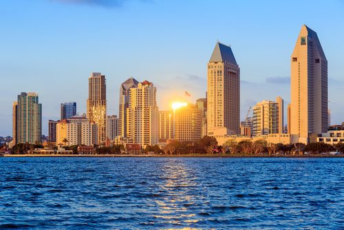 Sunset illuminates the skyline of san diego with its distinctive skyscrapers reflected in the waterfront.