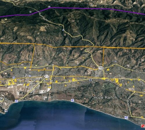 Satellite view of a coastal area with marked boundaries, showing roads, urban development, and mountainous terrain.