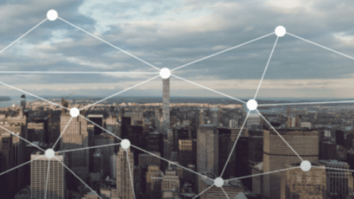 Aerial view of a city skyline with a digital overlay of white connecting dots and lines, symbolizing network connections.