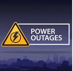 Warning sign with a lightning bolt symbol, indicating power outages, placed over a city skyline silhouette at night.
