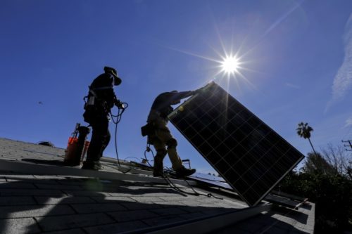 Workers installing solar panels on a roof.