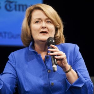 A woman in blue shirt holding a microphone.