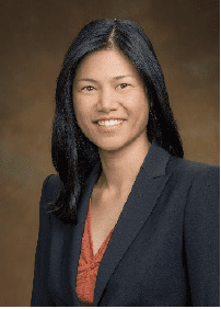 A woman in a suit smiles for the camera.