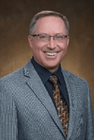 A man in a suit and tie smiling for the camera.