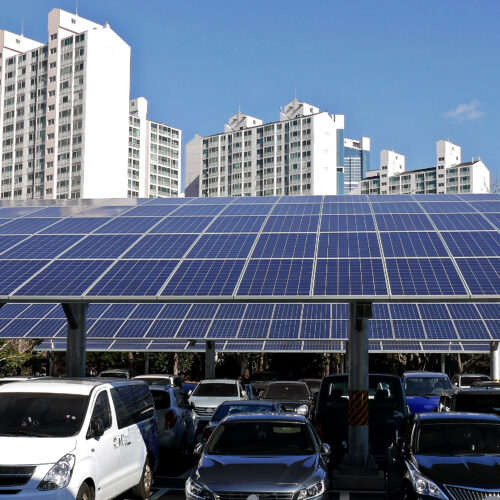 A parking lot with cars parked under a solar panel.