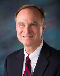 A man in a suit and tie smiling for the camera.