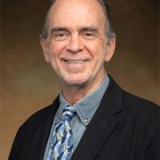 A man in a suit and tie smiling for the camera.