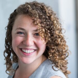 A woman with curly hair smiling for the camera.