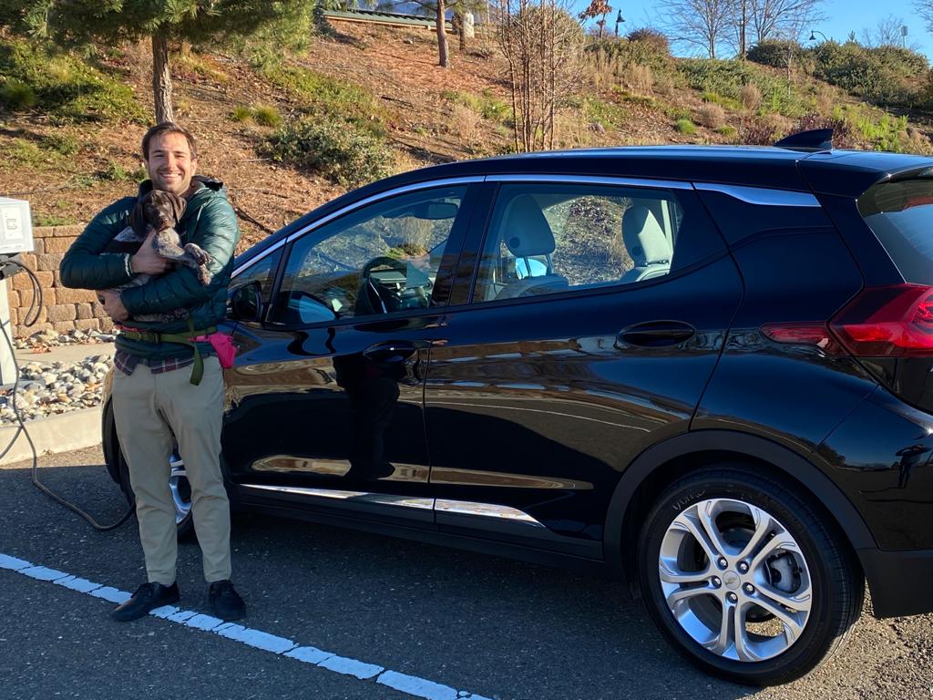 A woman standing next to a black car.