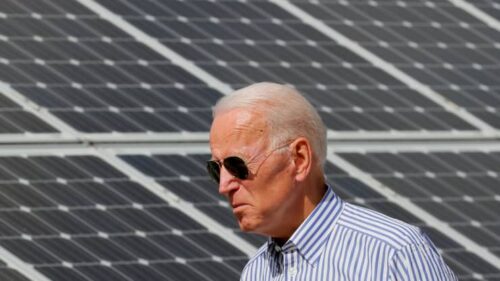 A man in sunglasses standing next to solar panels.