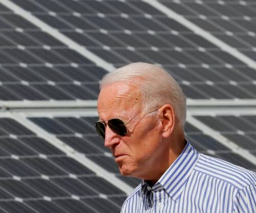 A man in sunglasses standing next to solar panels.