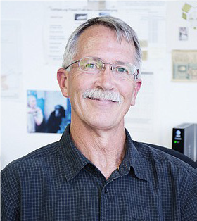 A man with glasses and a mustache wearing a black shirt.