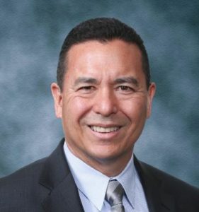 A man in suit and tie smiling for the camera.