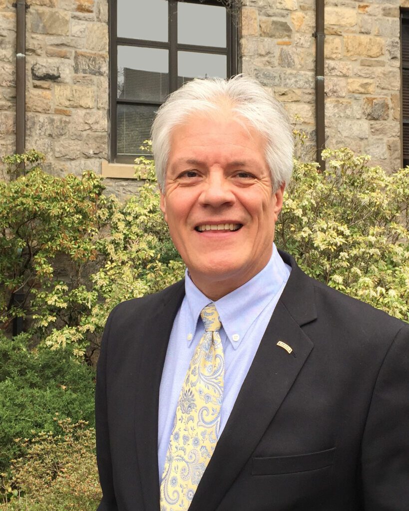 A man in suit and tie standing outside.