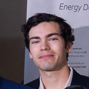 A man with curly hair and a suit jacket on.