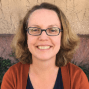 A woman with glasses smiling for the camera.