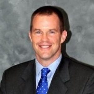 A man in suit and tie smiling for the camera.