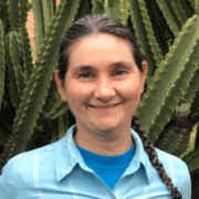 A woman with long hair and blue shirt smiling.