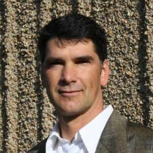 A man in a suit and tie standing next to a wall.