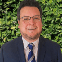 A man in a suit and tie smiling for the camera.