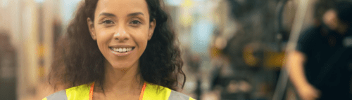 A woman in an orange vest smiling for the camera.