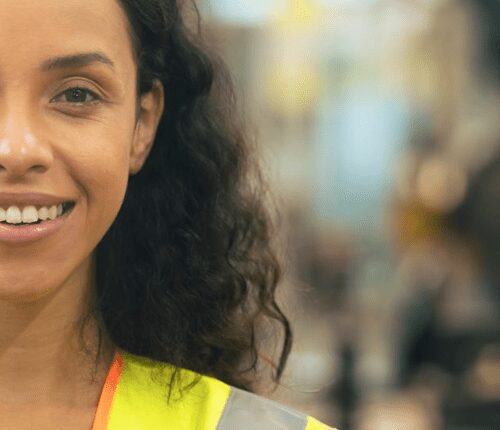 A woman in an orange vest smiling for the camera.
