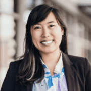 A woman in a suit and tie smiling for the camera.