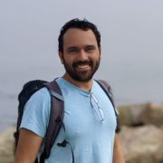 A man with a backpack standing on top of rocks.