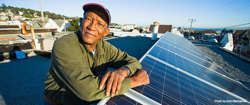 A man sitting on top of a roof next to solar panels.