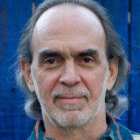 A man with long hair and beard wearing blue shirt.