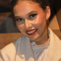 A woman with red lipstick and white jacket.