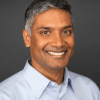 A man with grey hair and a blue shirt.