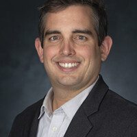 A man in a suit and tie smiling for the camera.