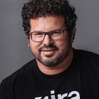 A man with curly hair and glasses wearing a black shirt.