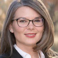 A woman with glasses and long hair wearing a suit.