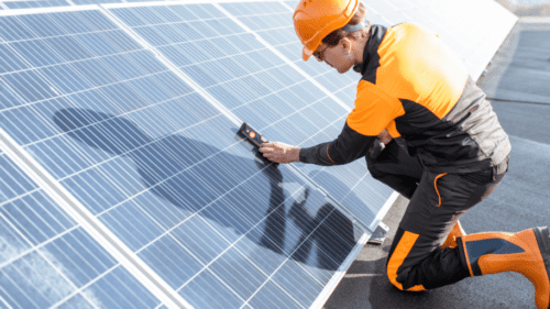 A man in an orange and black suit is working on solar panels.